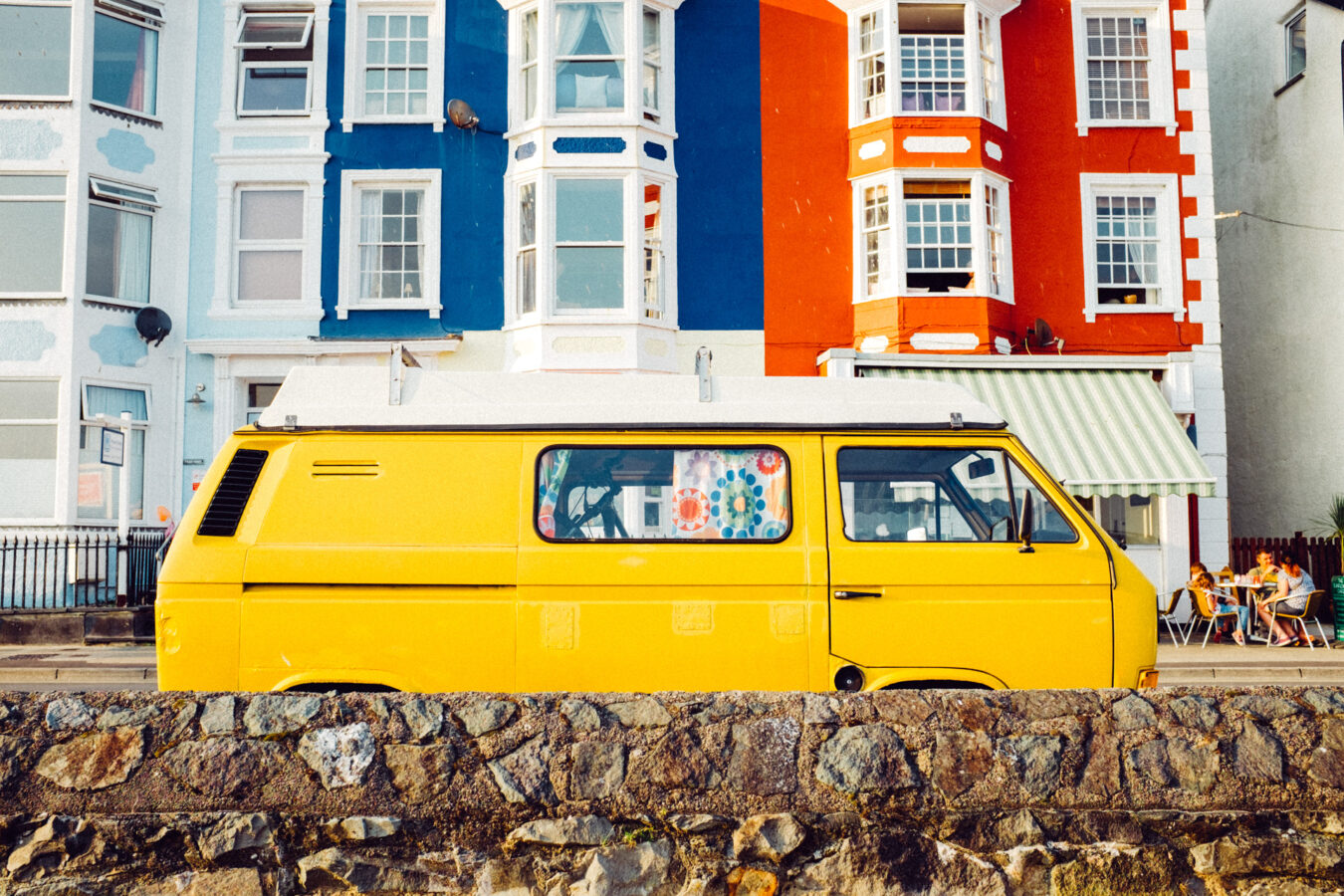 Yellow vintage campervan parked in a seaside town.