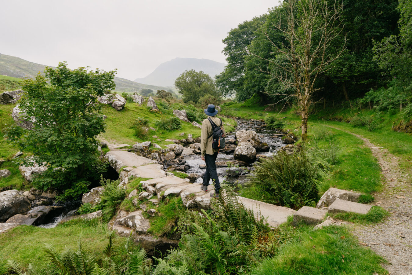 Man crossing a small footbridge in the mountains