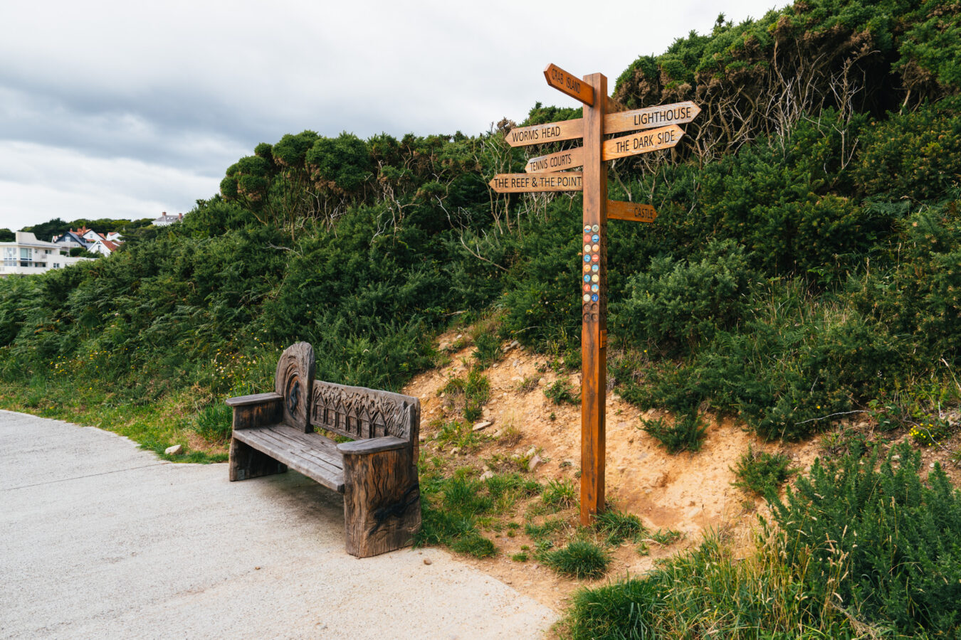 Bench and wooden direction sign along the walk to Langland Bay