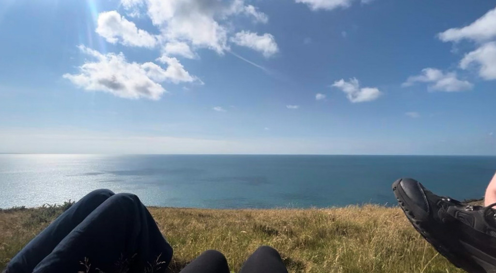Hikers resting on the grass, looking at the sea
